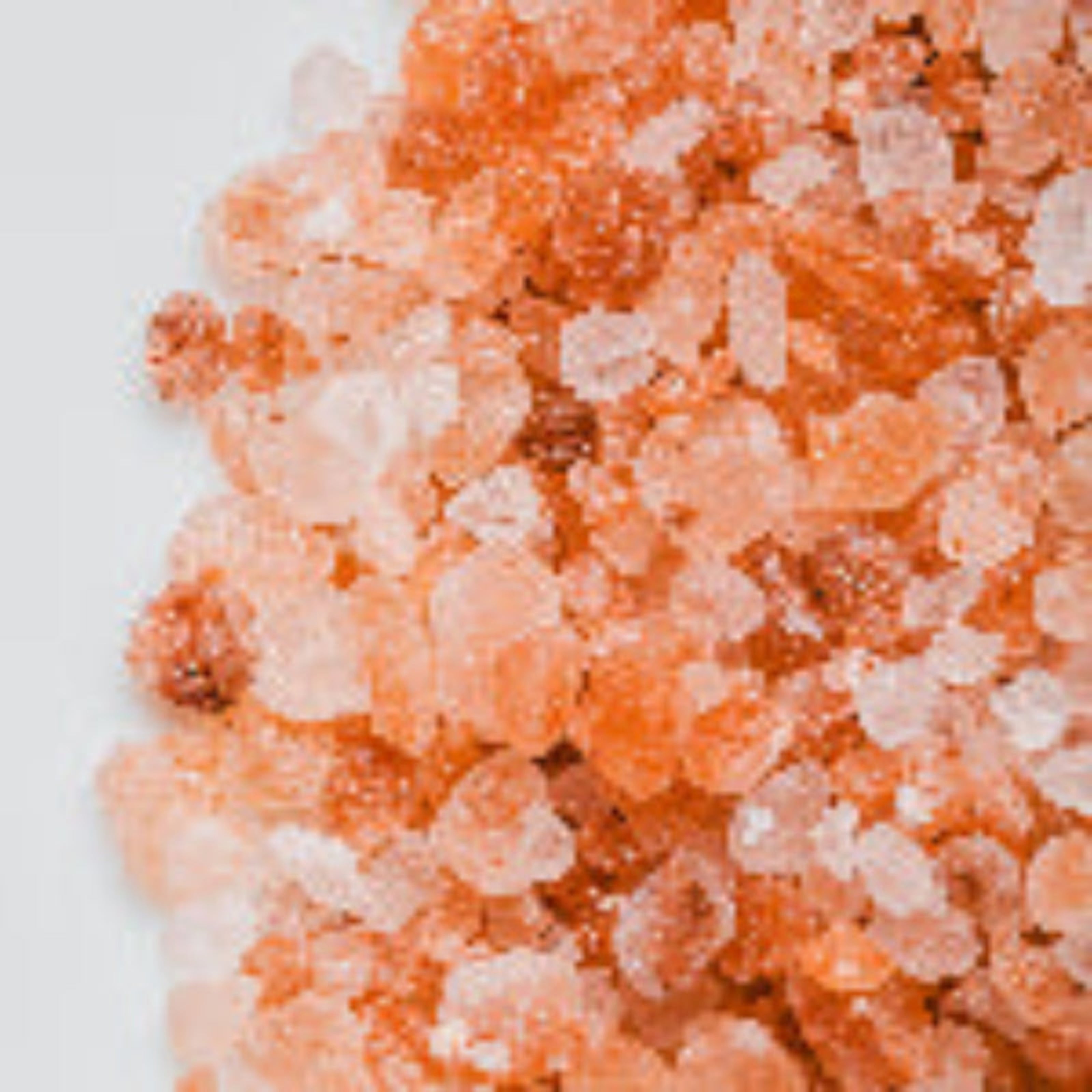 Close-up of pink Himalayan salt crystals on a white background